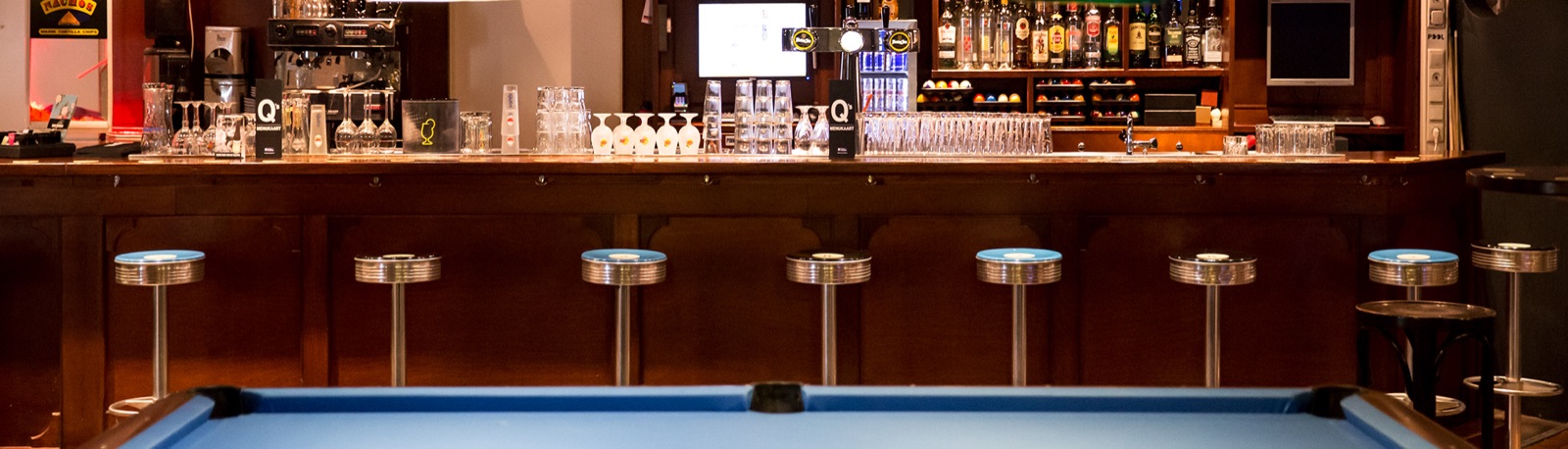 De bar van Q's met barkrukken en pooltafel